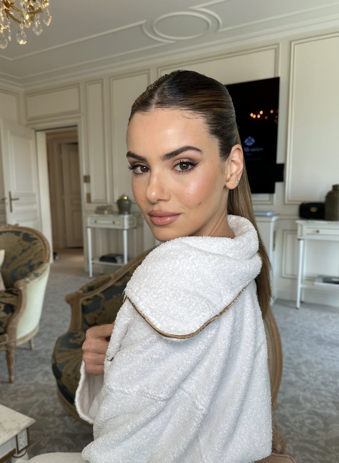 Actress Camila Queiroz at Paris Fashion Week 2025 for the Miu Miu show, soft waves and glam in a white robe, hair and makeup by Andrada Rusu
